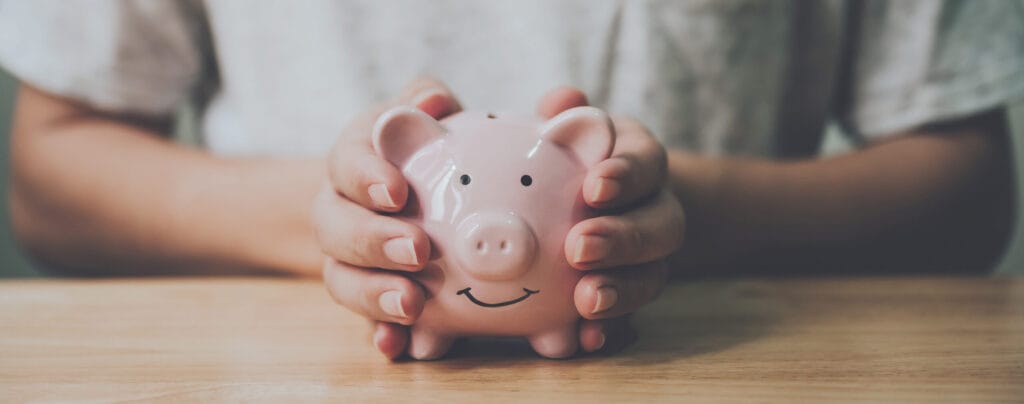 Hands holding a piggy bank to represent legal costs, risks and possible outcomes in a Will dispute.